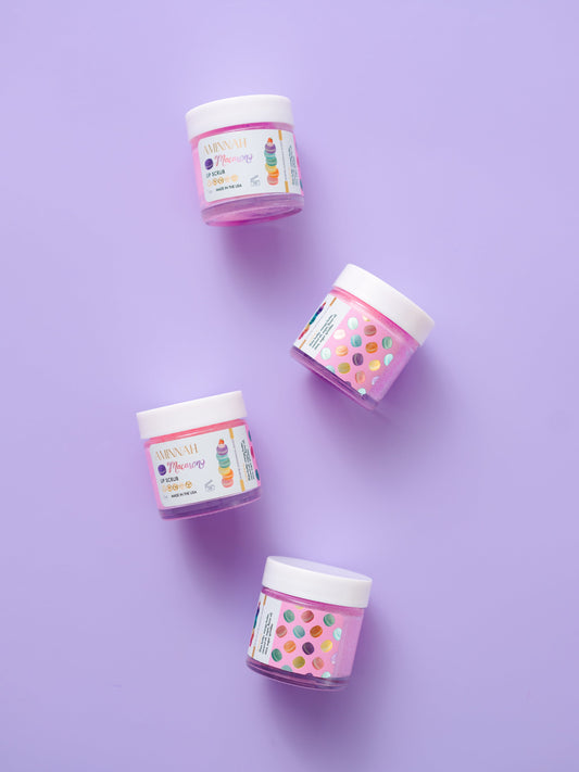 Two lip scrub jars standing on a purple background.
