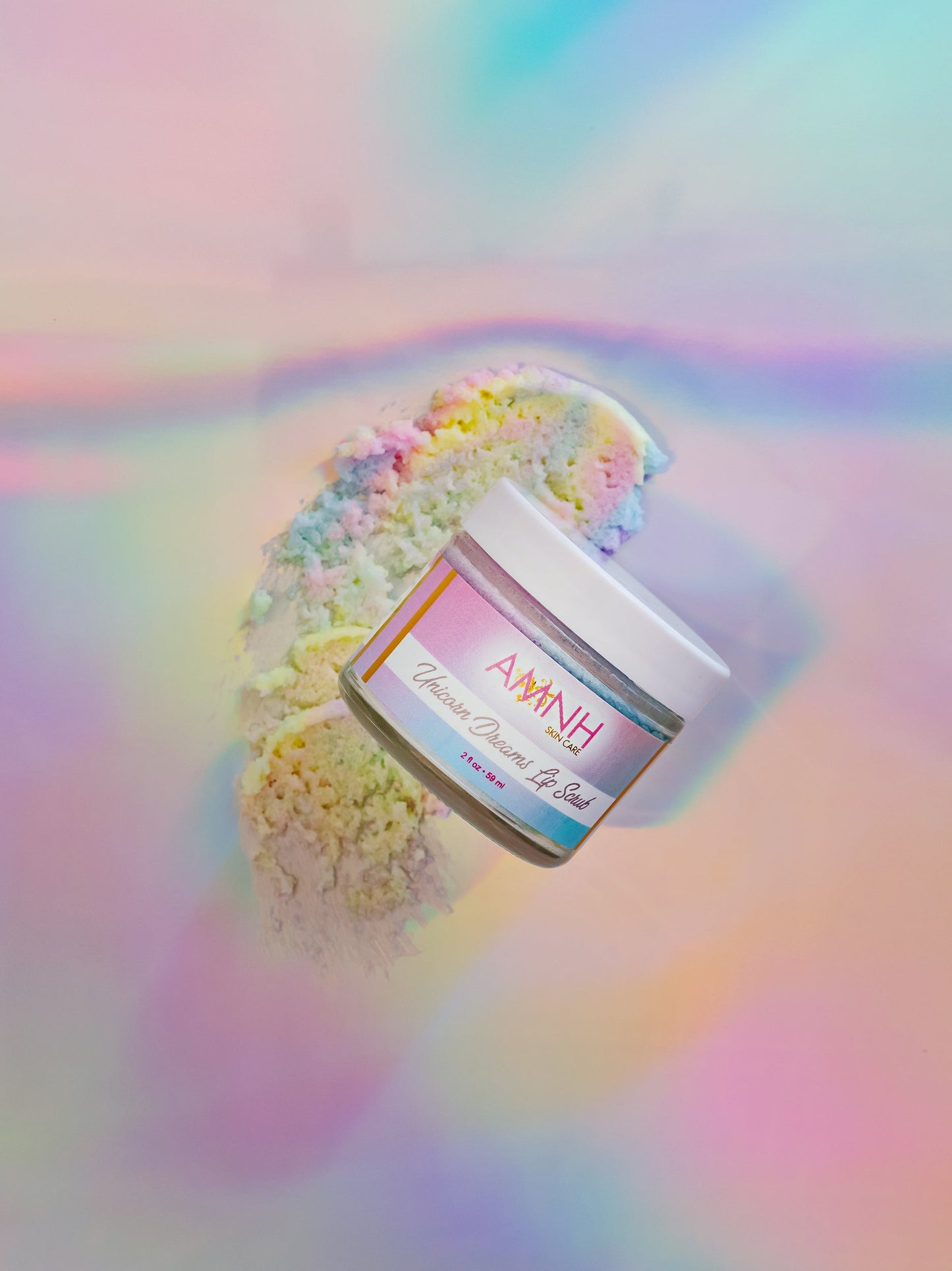 Jar of pastel lip scrub tilted on an iridescent background.