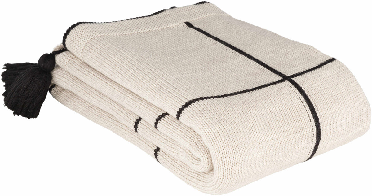 Folded cream knit throw blanket with black grid lines and a black corner tassel, seen at an angle