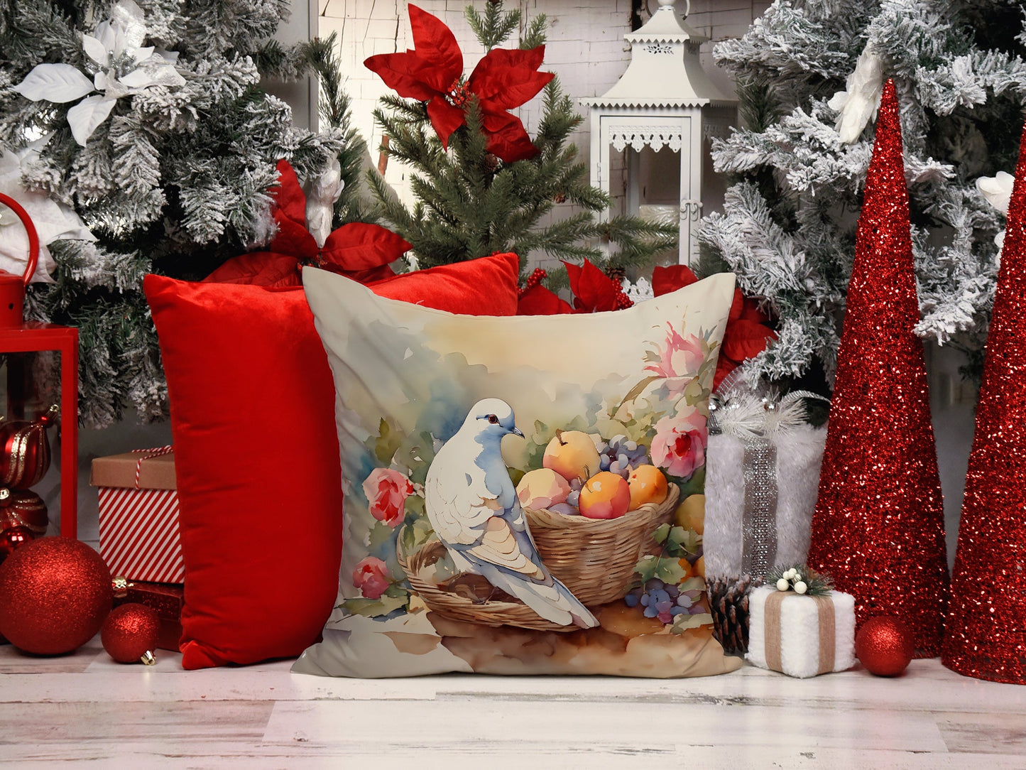The Dove artwork pillow in a winter setting, among red cushions, poinsettia and frosted greenery.