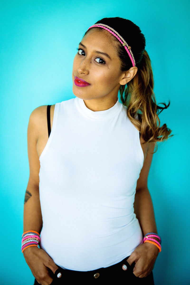 Model in a white top wearing a braided headband and colorful hair ties as bracelets