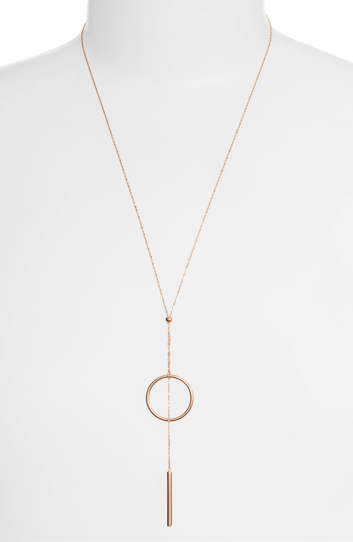 Lariat necklace on a white bust form, the circle and bar hanging low on the chest