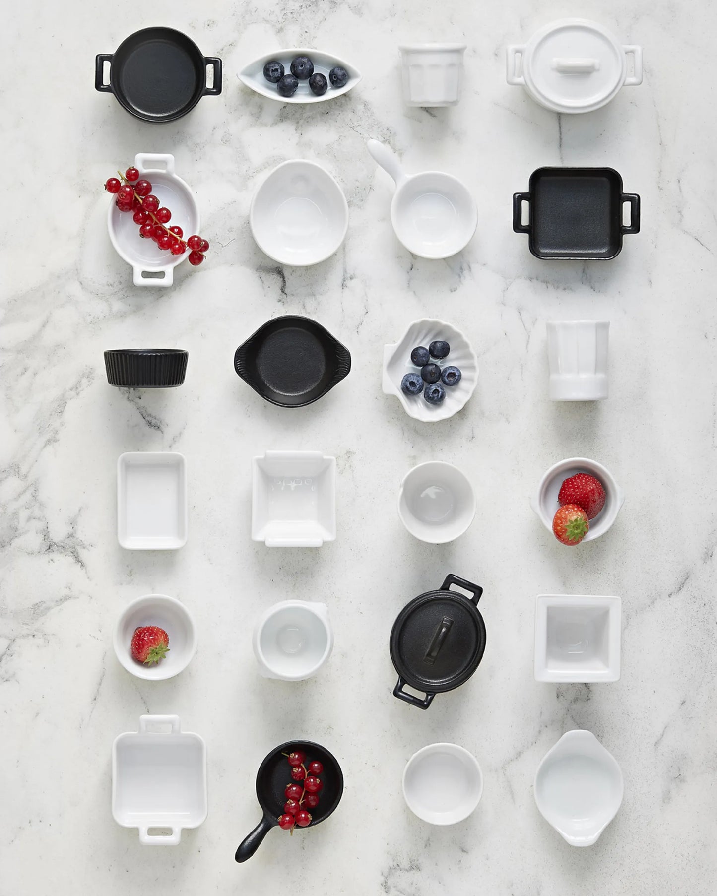 Overhead flat lay of the range in black and white, several pieces holding fruit.