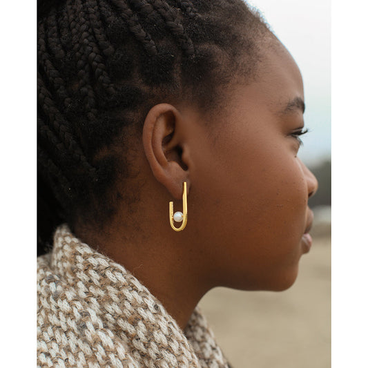 Woman in profile wearing a J hoop earring with a freshwater pearl and a knit scarf