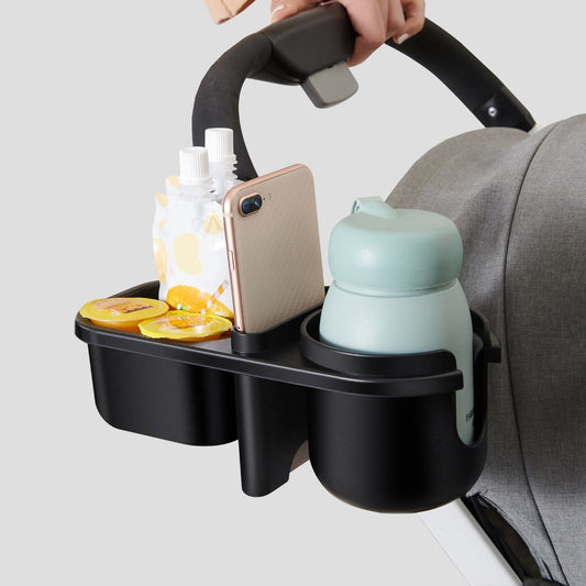 Clamp mounted on a stroller handlebar holding a phone, a snack and a cup.