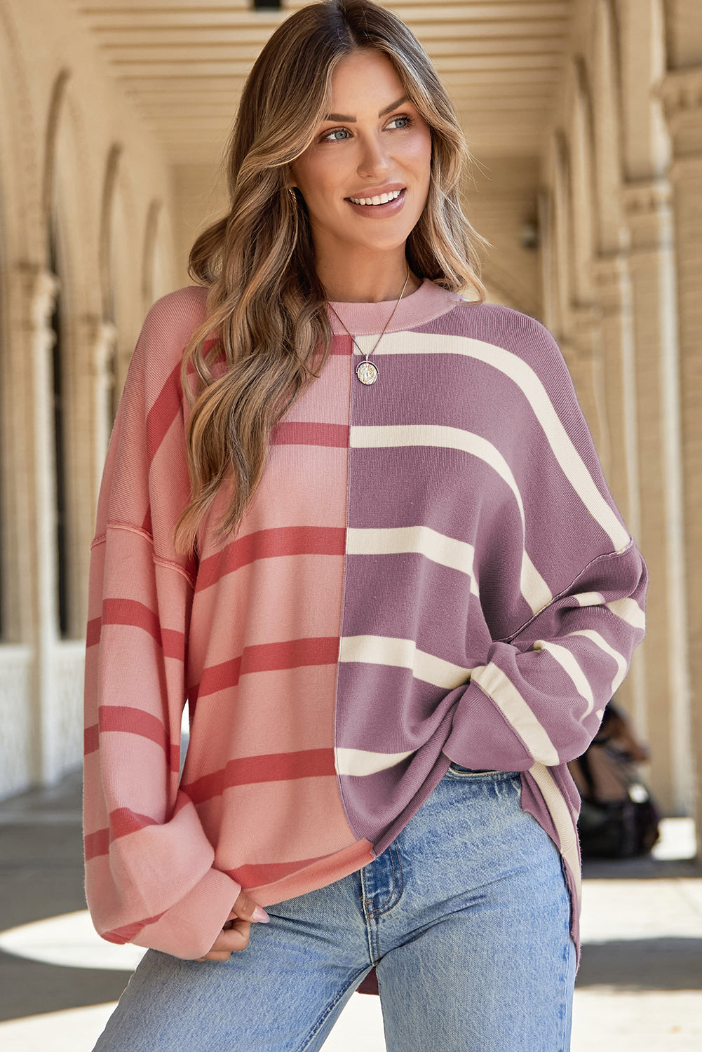 Pink and mauve oversized sweater, front view under an arcade