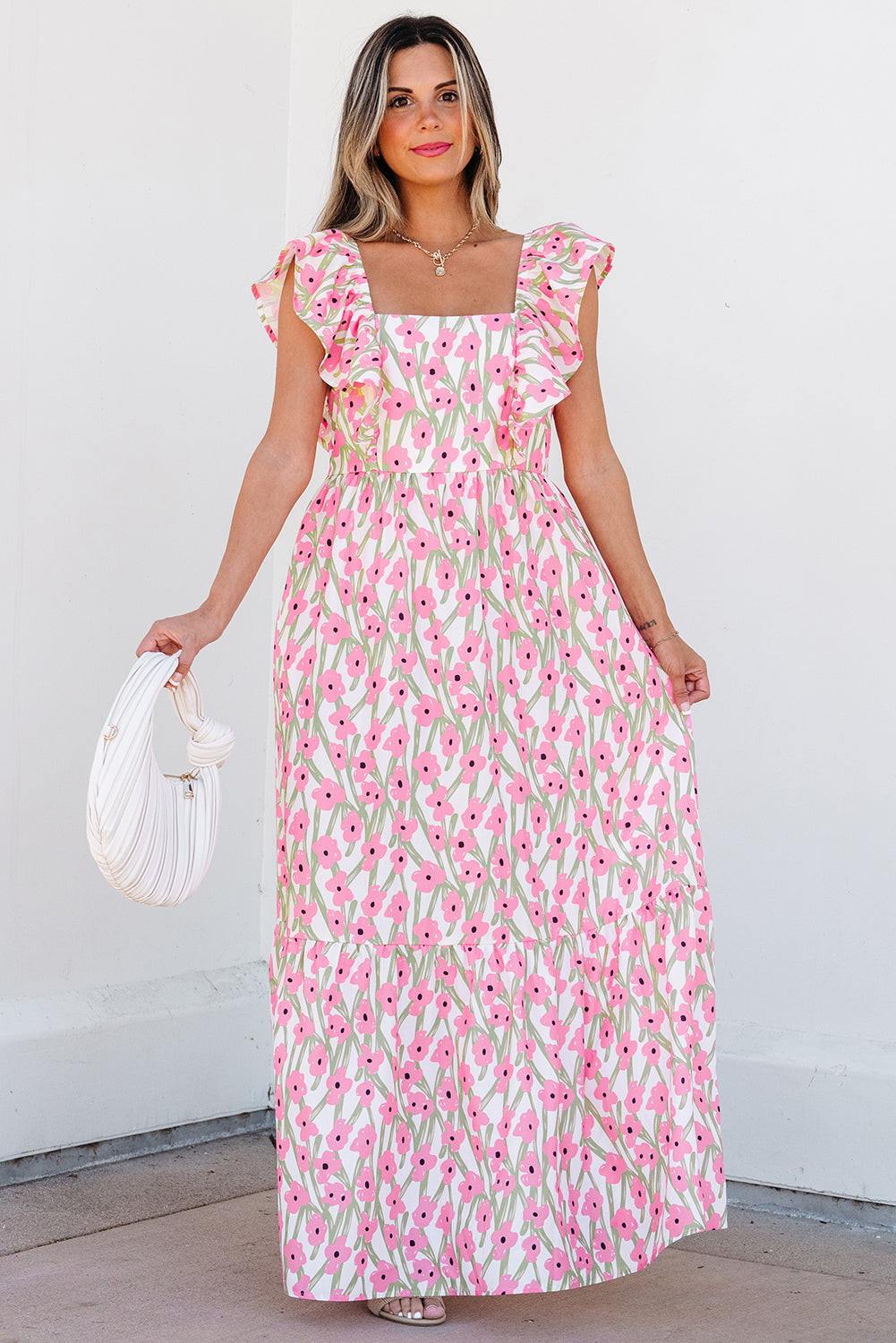 Pink floral square neck maxi dress, model holding the skirt