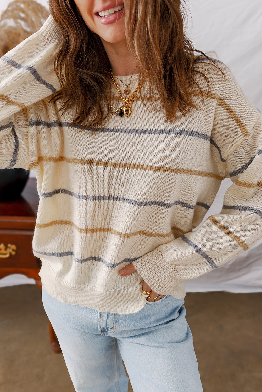 Cream striped sweater, model with a hand in her hair