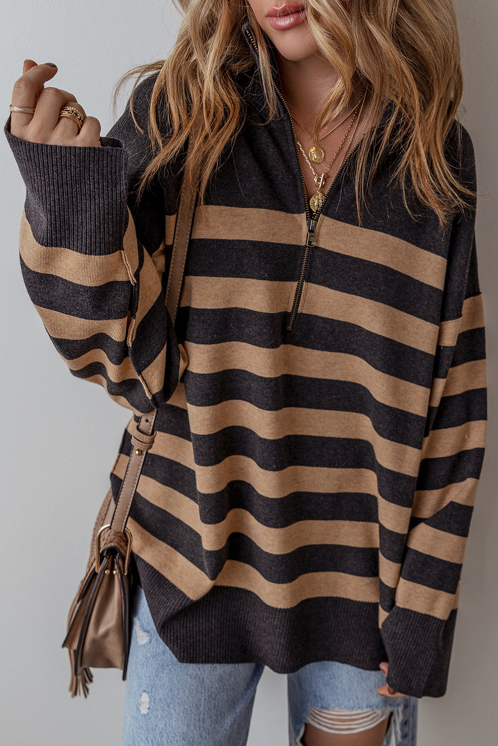 Black and camel striped sweater, model raising one arm