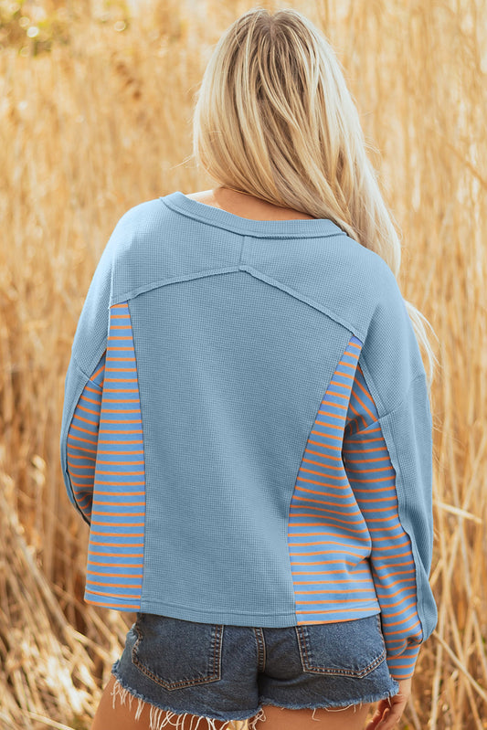 Back of the dusty blue pullover with striped side panels