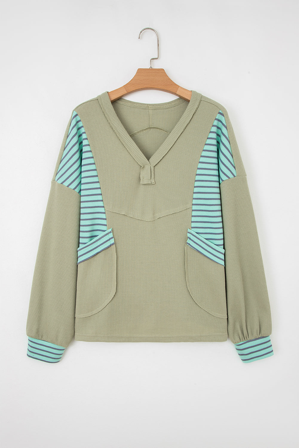 Sage green waffle knit V-neck pullover on a hanger