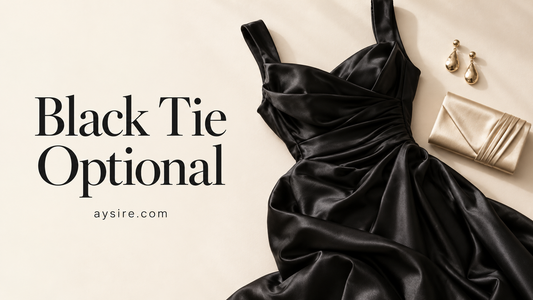 Black Tie Optional, black satin dress with a champagne clutch and gold earrings on a cream background