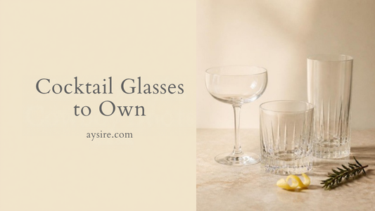 Cocktail Glasses to Own. Empty coupe, rocks and highball glasses on a stone counter with a lemon twist and rosemary.