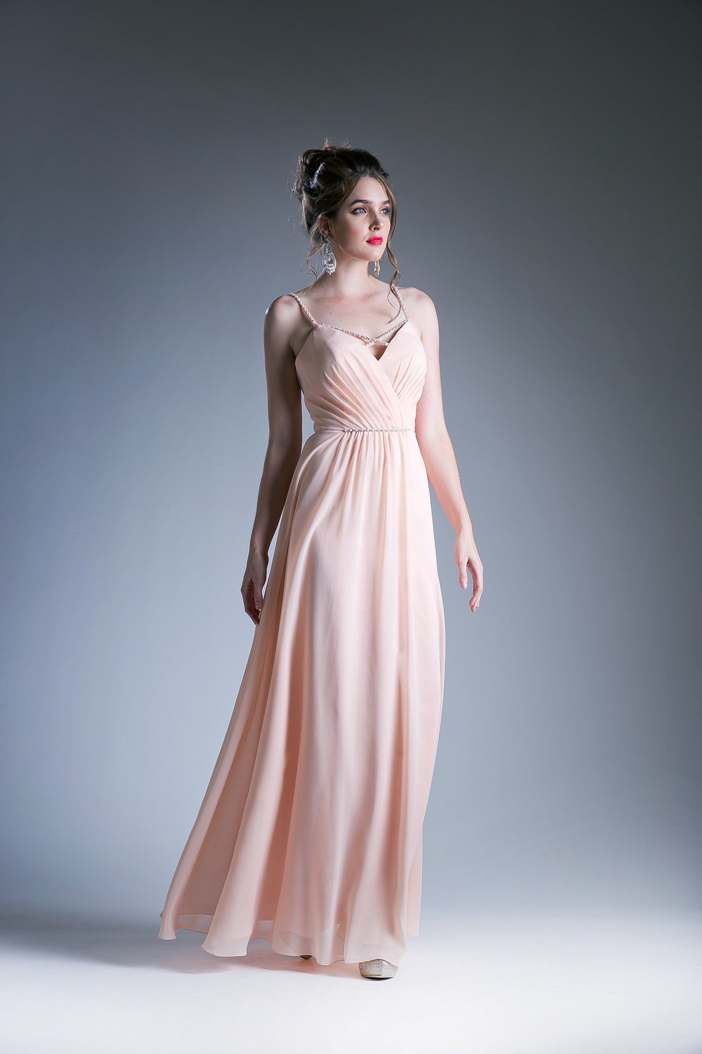Peach V-neck evening gown with spaghetti straps and a beaded waistband.