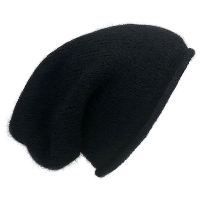 Black knit beanie seen from the side, slouching at the back above a rolled brim