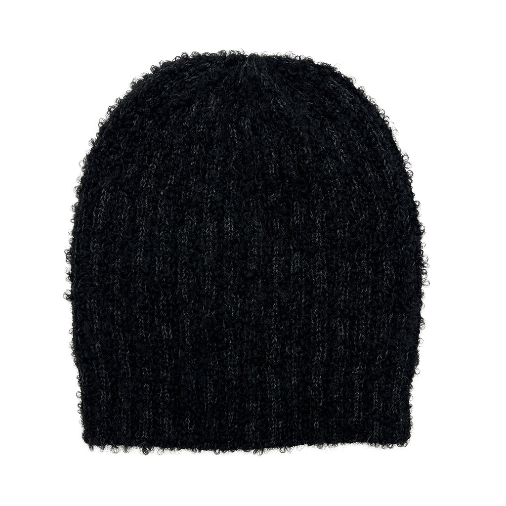 Black alpaca beanie laid flat, its looped yarn giving a fuzzy texture over faint ribbed stripes