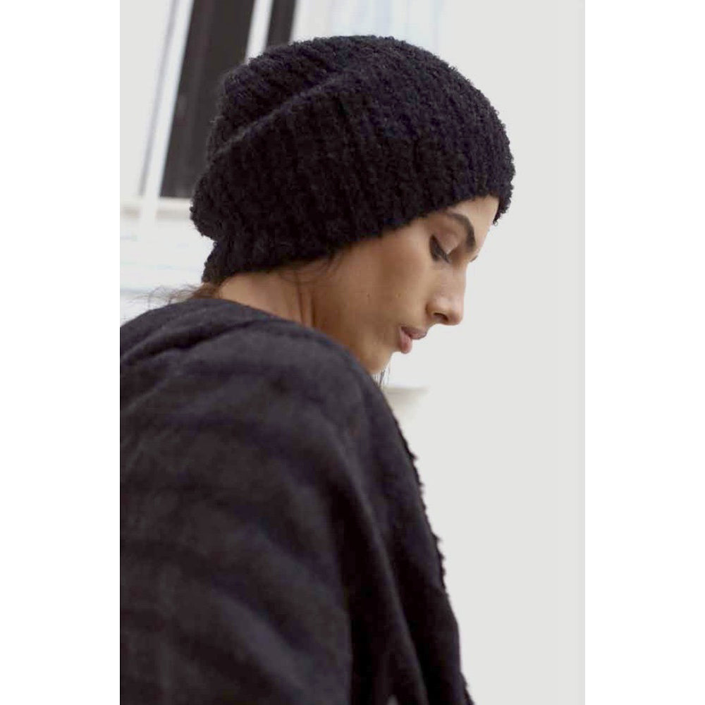 Side view of the black loop knit beanie on a model, slouching at the back of the head