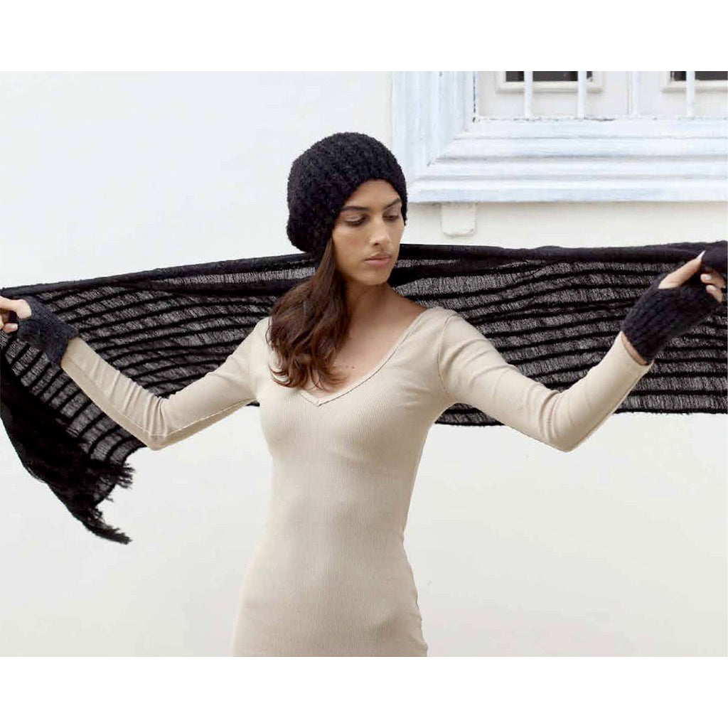 Model in the black alpaca beanie holding a long black striped scarf open behind her