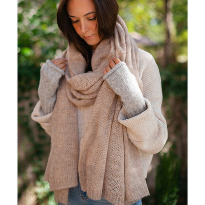 Woman in a cream sweater and an oatmeal knit scarf wearing heather gray wrist warmers on both hands