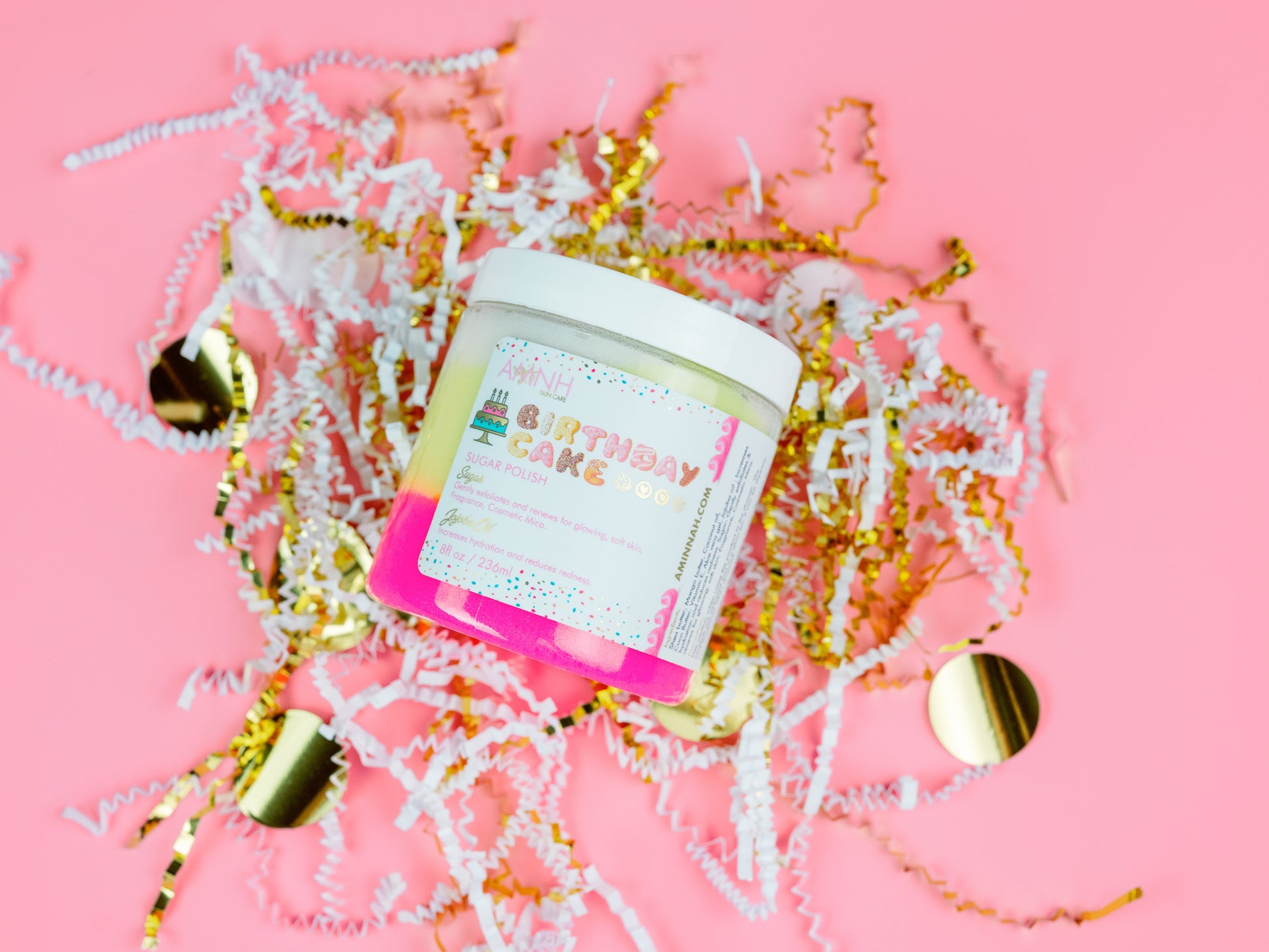 Scrub jar standing in gold and white paper shred on a pink background.