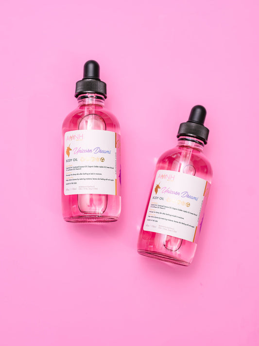 Two pink body oil bottles with black dropper caps on a pink background.