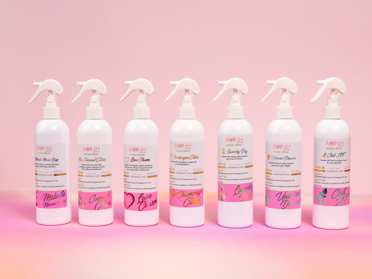 Row of AMNH room spray bottles seen from a low angle on pink.