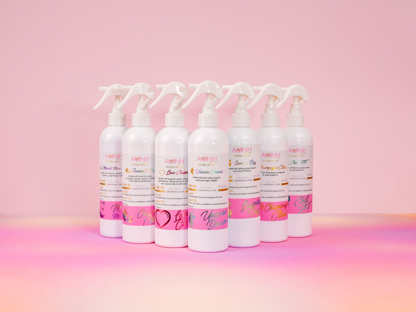 Row of AMNH room spray bottles lined up on pink.