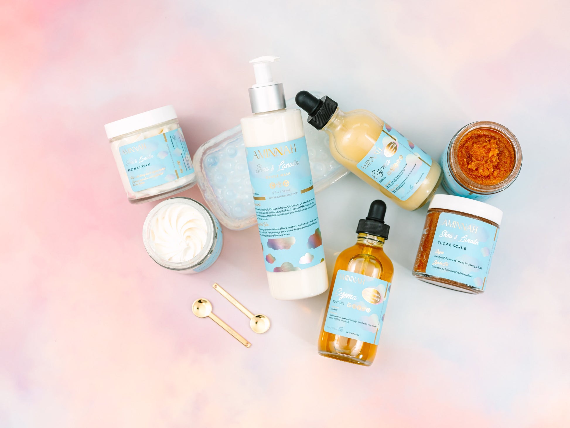 Serum bottles and a jar with gold spoons on pastel.