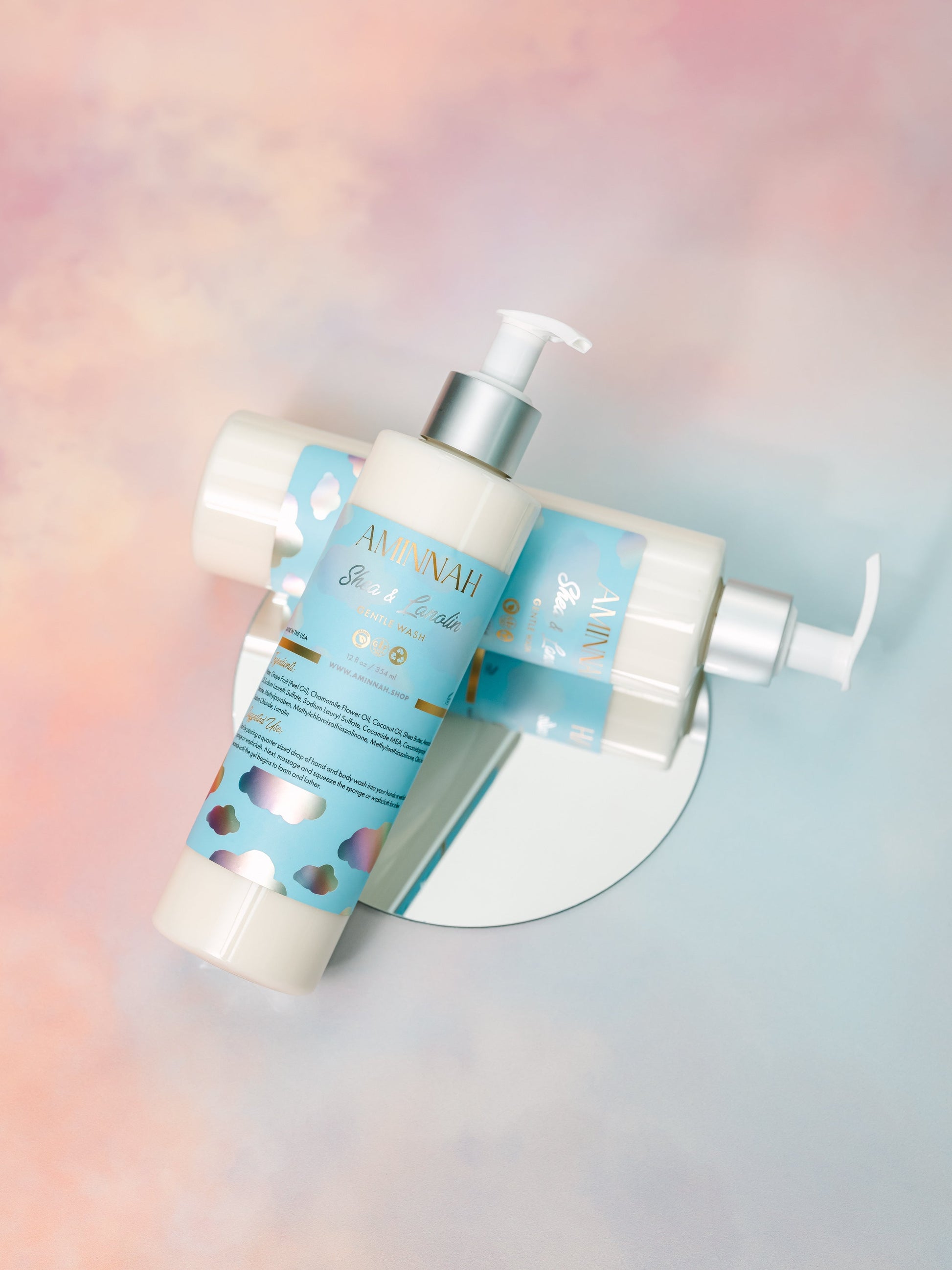 Two cleanser bottles crossed over each other on pastel.