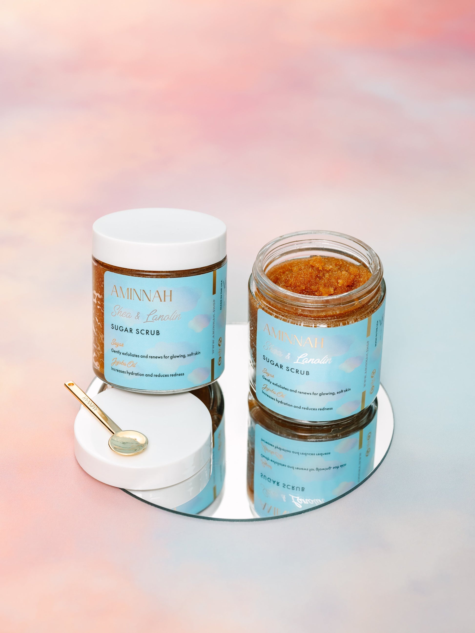 Two stacked jars on a white tray with a gold spoon, on a pastel background.