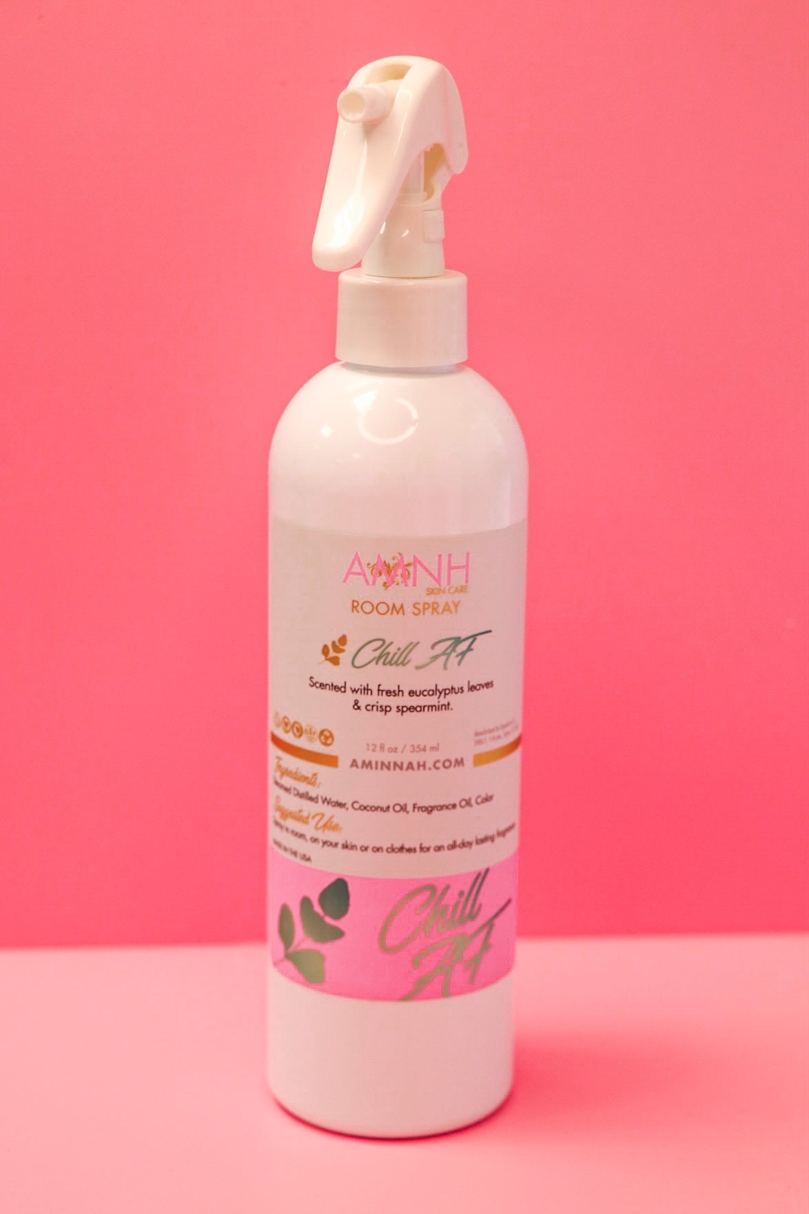 Room spray bottle standing upright against a hot pink background.