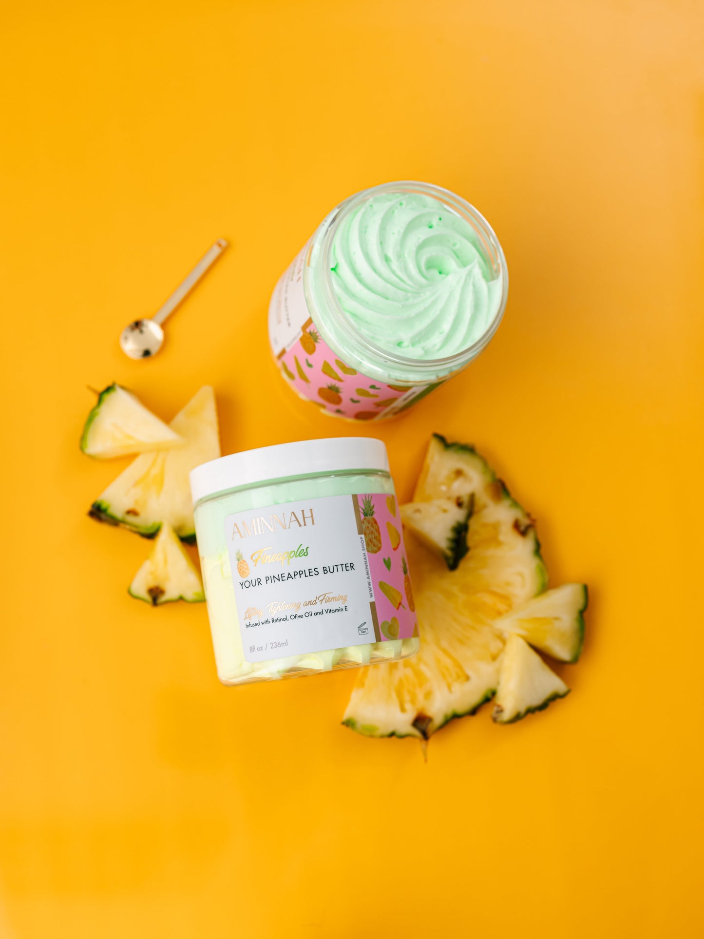 Jar of green whipped butter with fresh pineapple wedges around it on yellow.