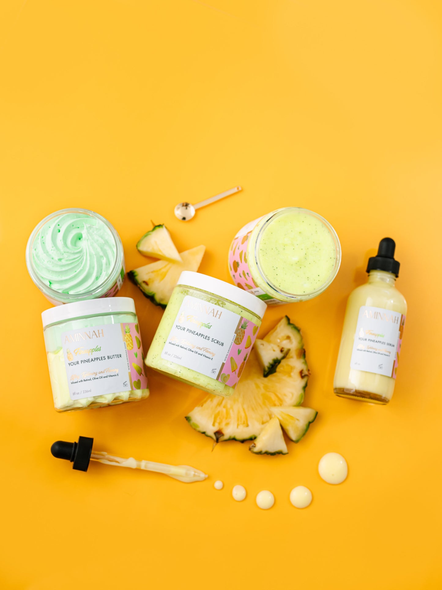 Flat lay of two jars and a dropper bottle with pineapple wedges on yellow.