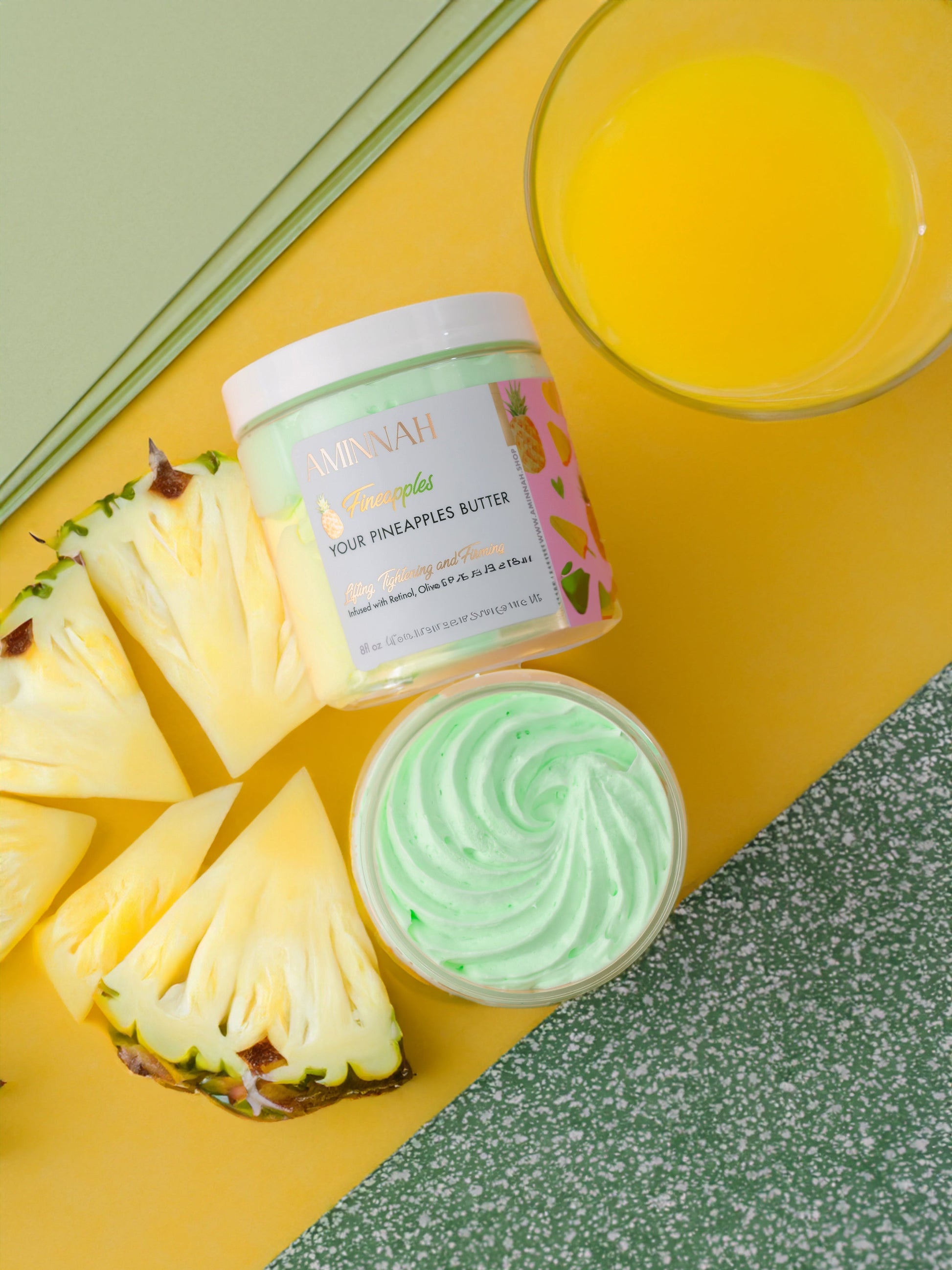Two jars on a green and yellow background with pineapple slices and a glass of juice.