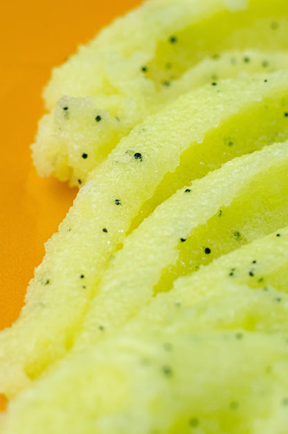 Streak of pale green sugar scrub drawn across a yellow background.