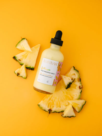 Dropper bottle lying among fresh pineapple wedges on yellow.