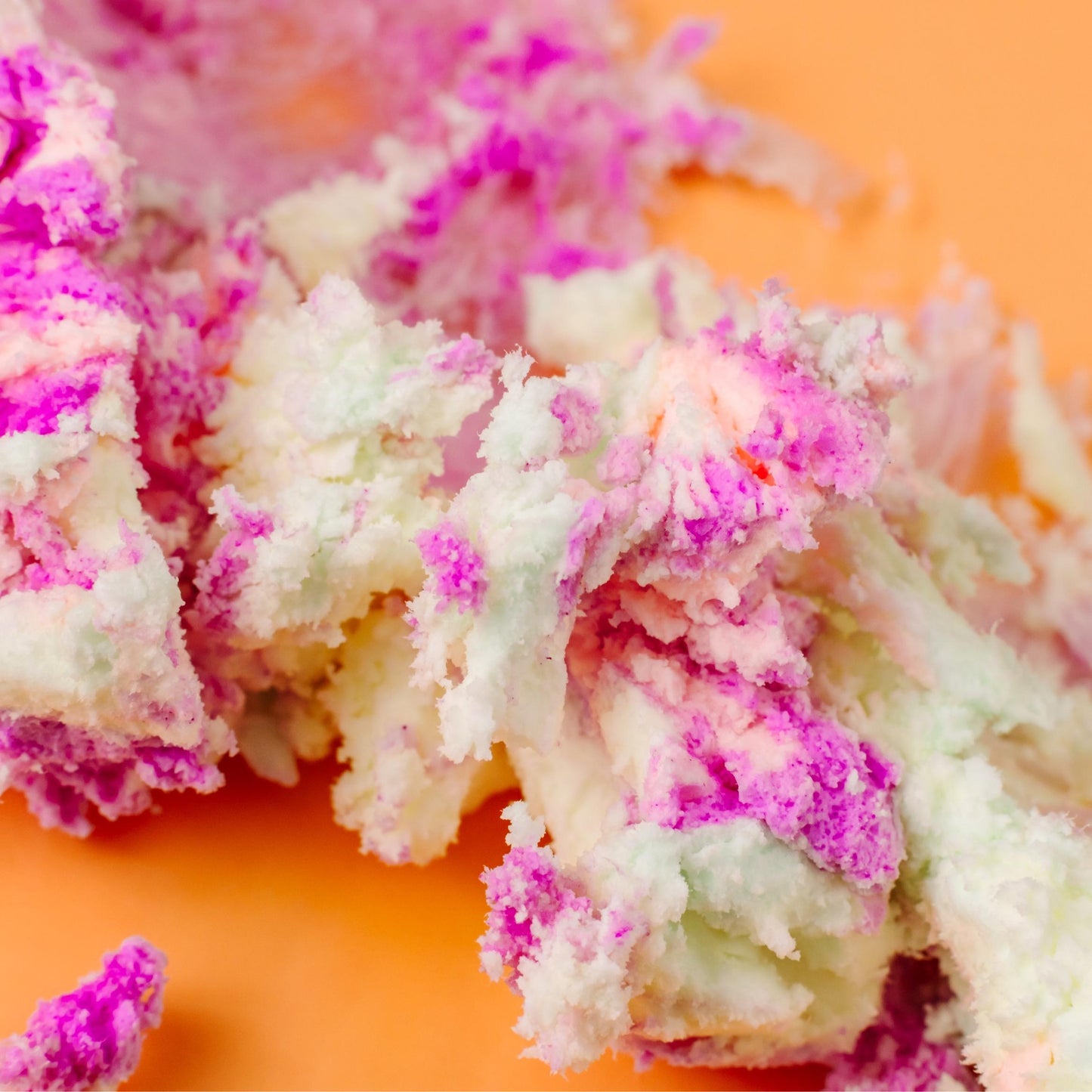 Clusters of pink and white whipped butter on orange.