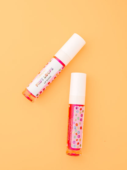 Two lip gloss tubes lying side by side on an orange background.