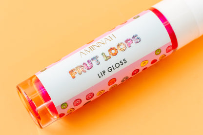 Lip gloss tube lying on orange with the Frut Loops label facing up.