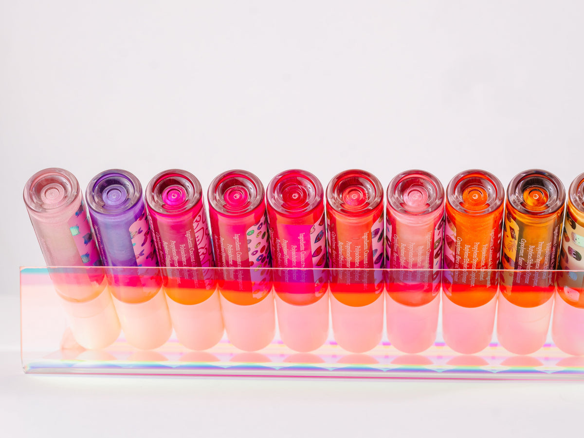 Row of lip gloss tubes standing together in a clear tray.