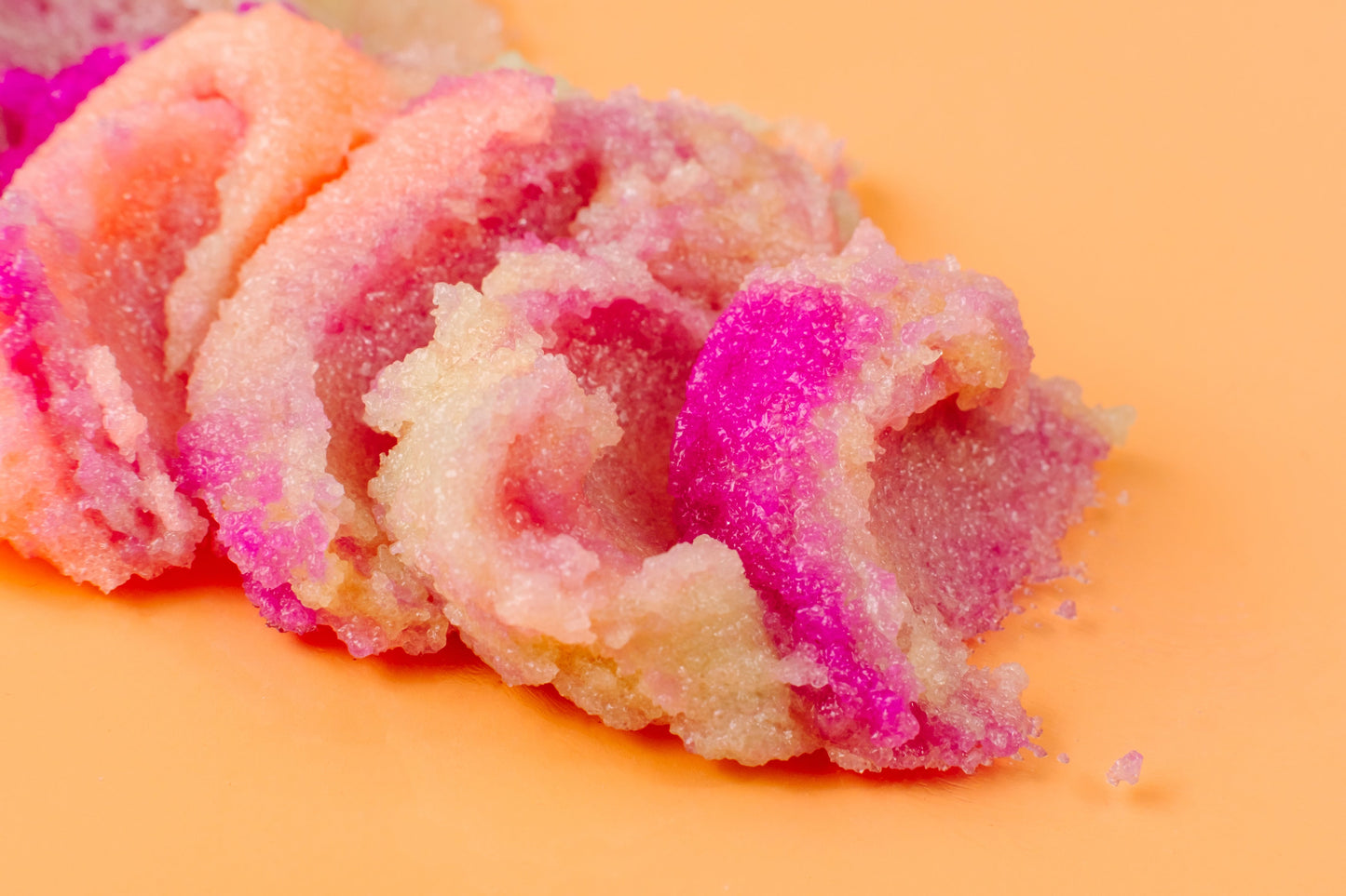 Twisted ribbon of pink and cream sugar scrub on peach.