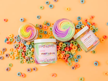 Two jars of rainbow whipped butter among coloured cereal loops on orange.