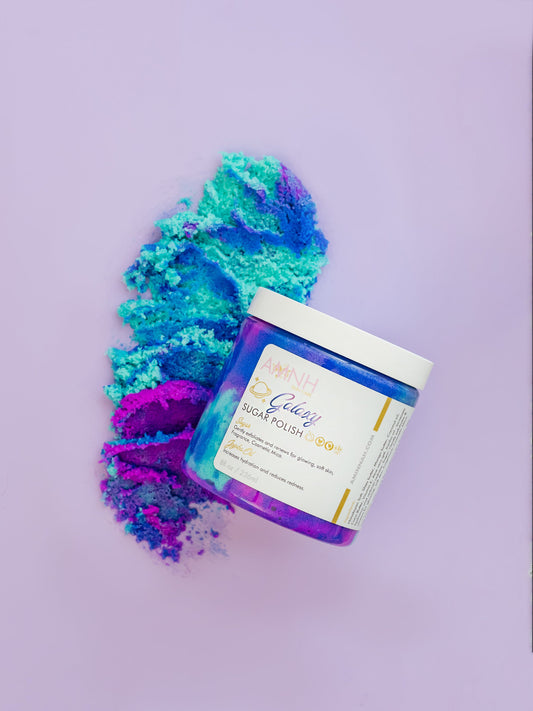 Jar with blue and purple sugar scrub spilling out onto a purple background.
