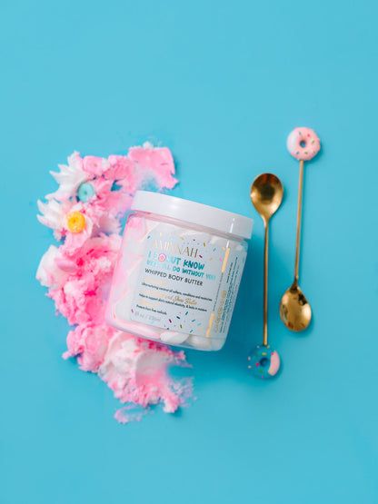 Open jar of pink whipped butter with a gold spoon beside it on blue.