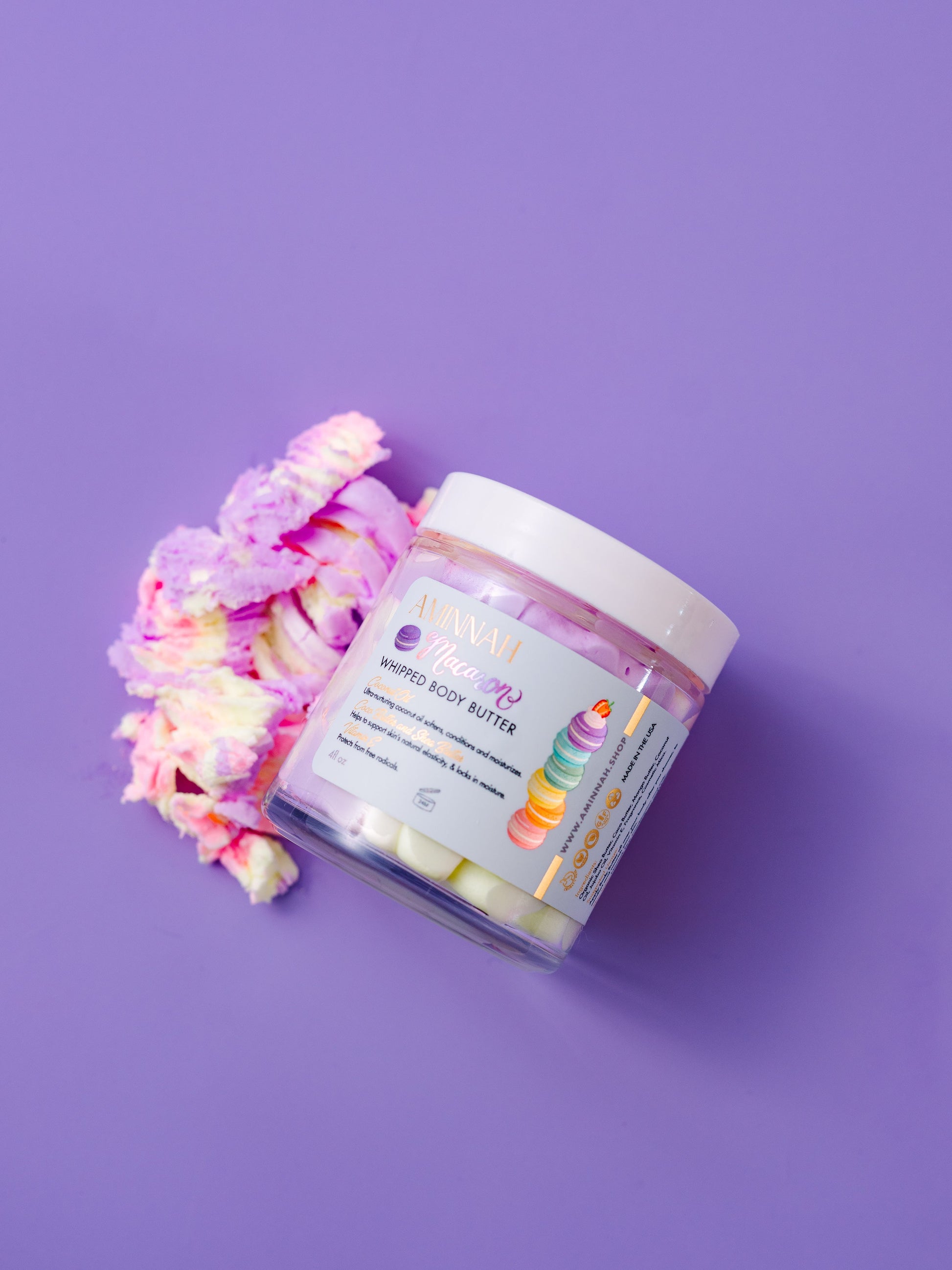 Open jar with a pink and purple whipped swirl on a purple background.