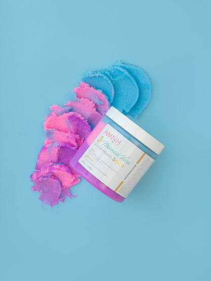Jar with pink and blue sugar scrub spilling out on a blue background.