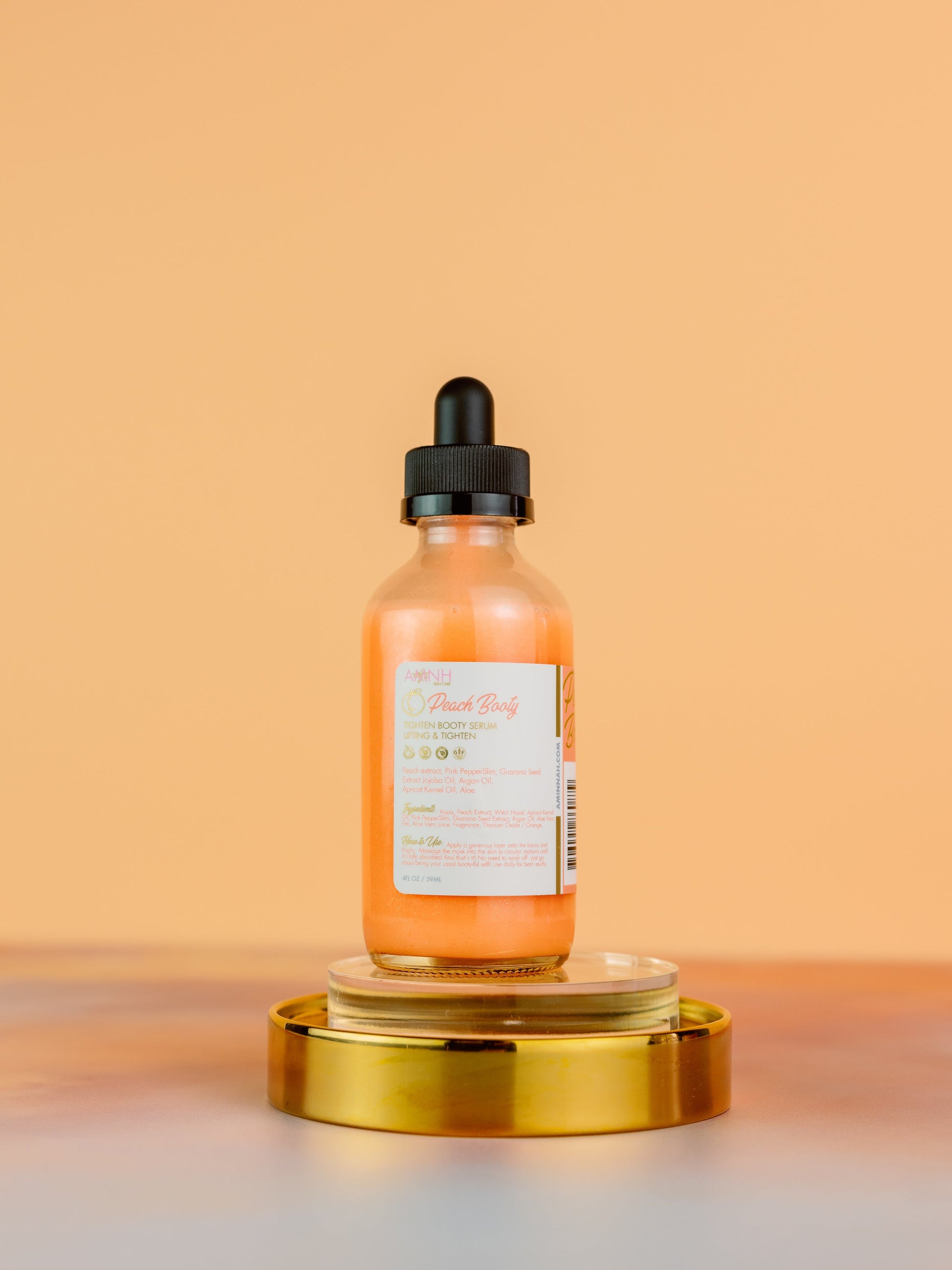 Serum bottle standing on a gold pedestal against orange.