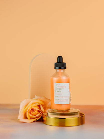 Serum bottle on a gold pedestal with a peach rose beside it.