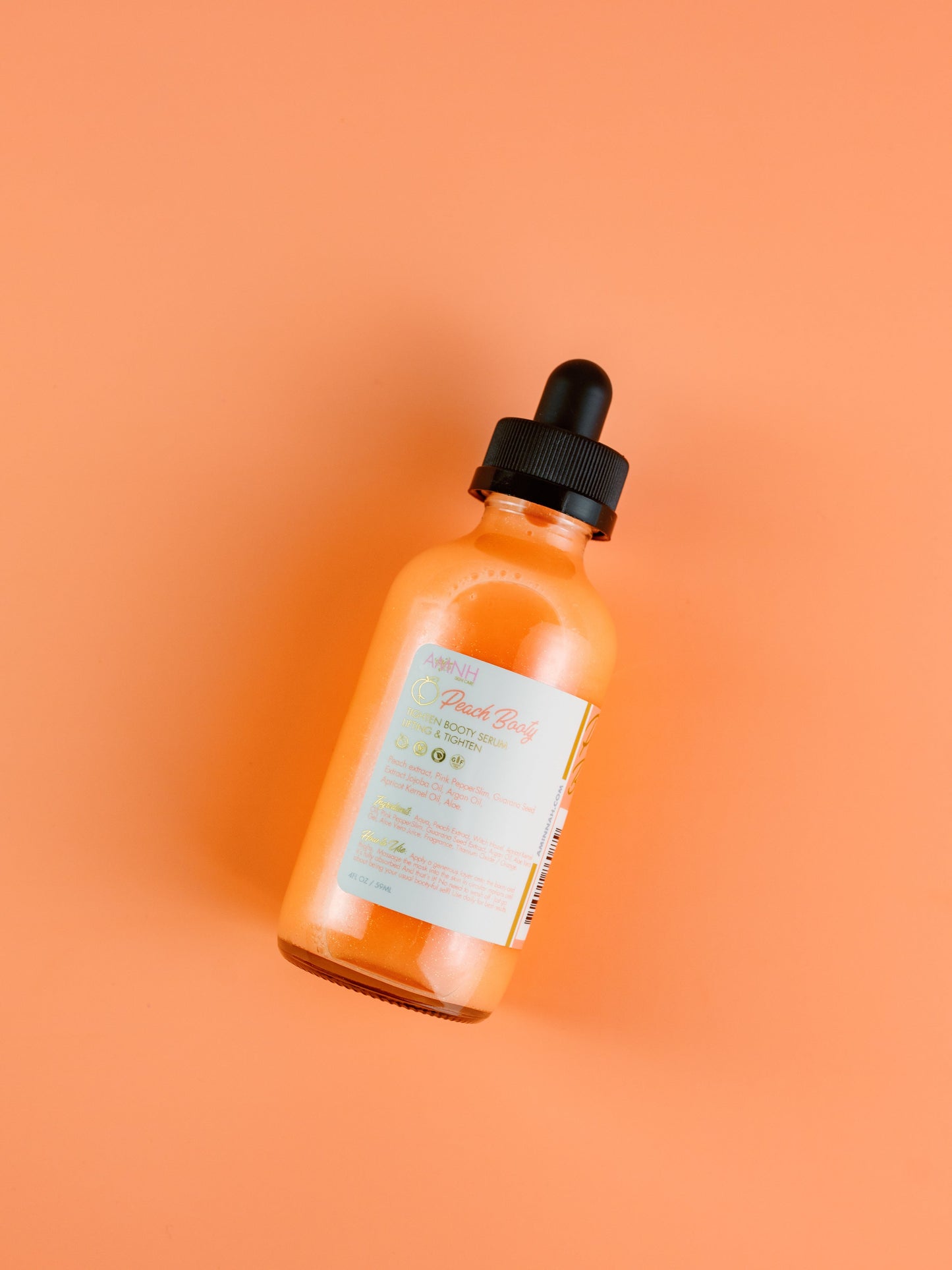 Single dropper bottle lying flat on an orange background.