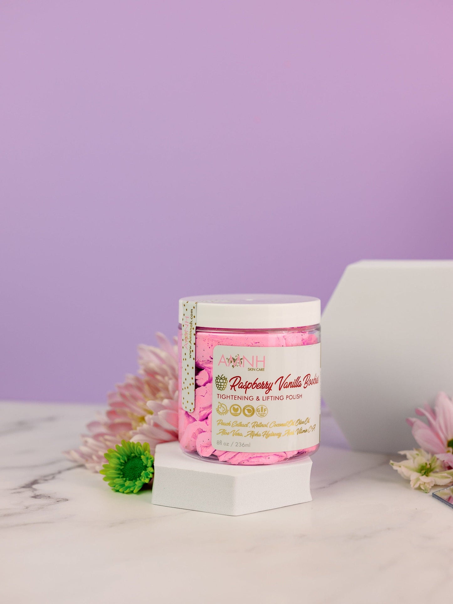 Jar with flowers and a white gift box on a lilac background.